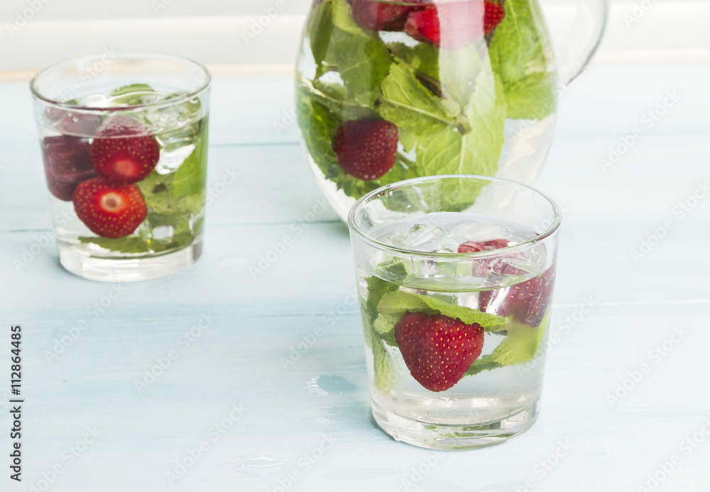 Summer cold drink with strawberry, mint and ice on a light backg Summer cold drink with strawberry, mint and ice on a light backg