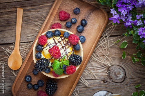 Tasty ice cream dessert with fruit in a waffle bowl.