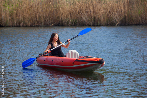 The girl athlete swimming, kayaking on the lake.