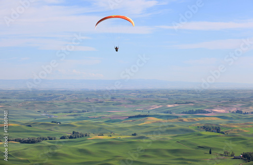 Para glider up in the sky above rolling hills of Palouse in Washington state.