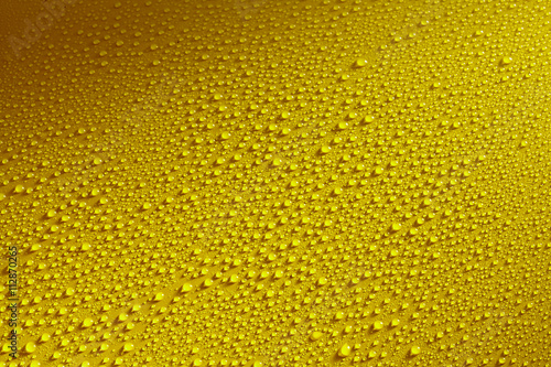 Water drops beading on a yellow metal surface