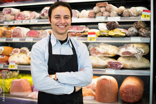 Bild auf Leinwand Smiling shopkeeper at work in a grocery store