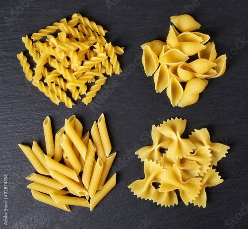 Various types of pasta on black background, from above photo