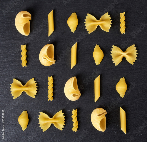 Various types of pasta on black background, from above photo