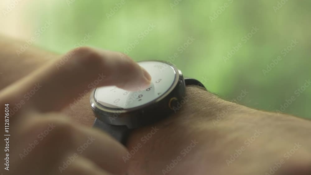 Man hands gestures on a round screen modern smartwatch calling a phone number by using the dial screen. Beautiful green exterior outdoor nature background bokeh. Man hands gestures on a round screen modern smartwatch calling a phone number by using the dial screen. Beautiful green exterior outdoor nature background bokeh.