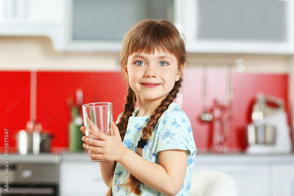 Cute little girl holding glass of water in kitchen Cute little girl holding glass of water in kitchen