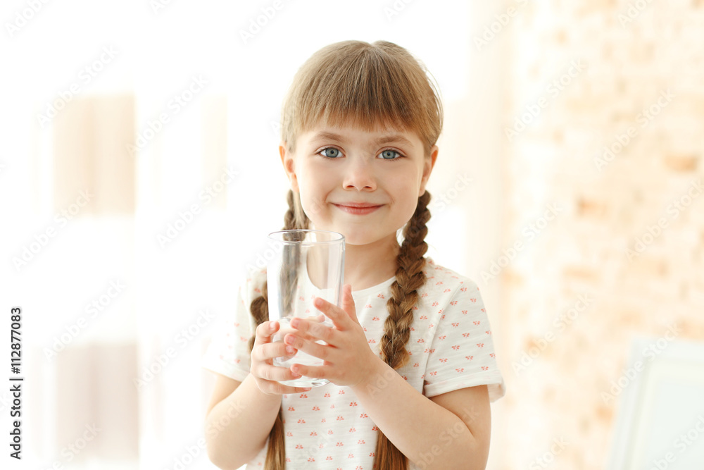 Cute little girl holding glass of water on light background Cute little girl holding glass of water on light background