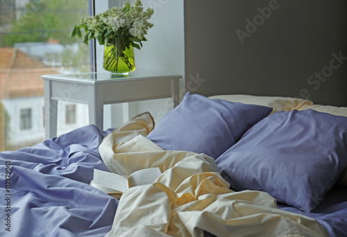 Unmade bed with crumpled bl...