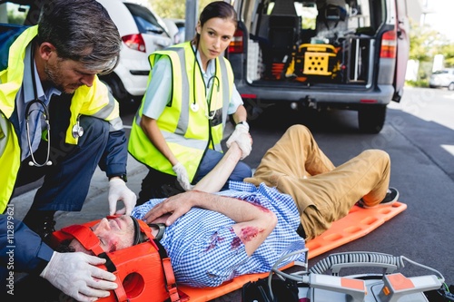 Emergency medical technicians healing injured man on road photo