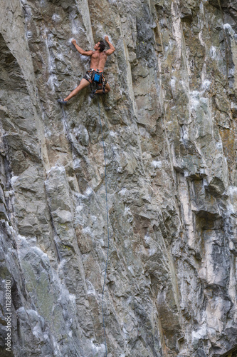 Rock Climber climbing a steep cliff on a mountain. Taken near Squamish, British Columbia, Canada