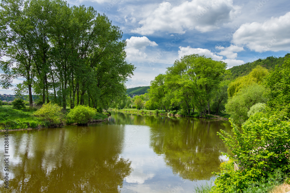 Summer landscape with green grass, road, river and clouds