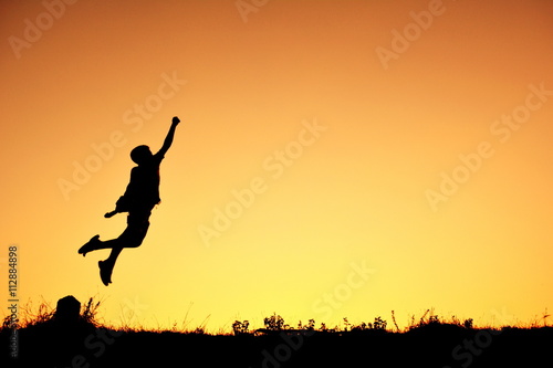 Silhouette a boy flying at sky sunset