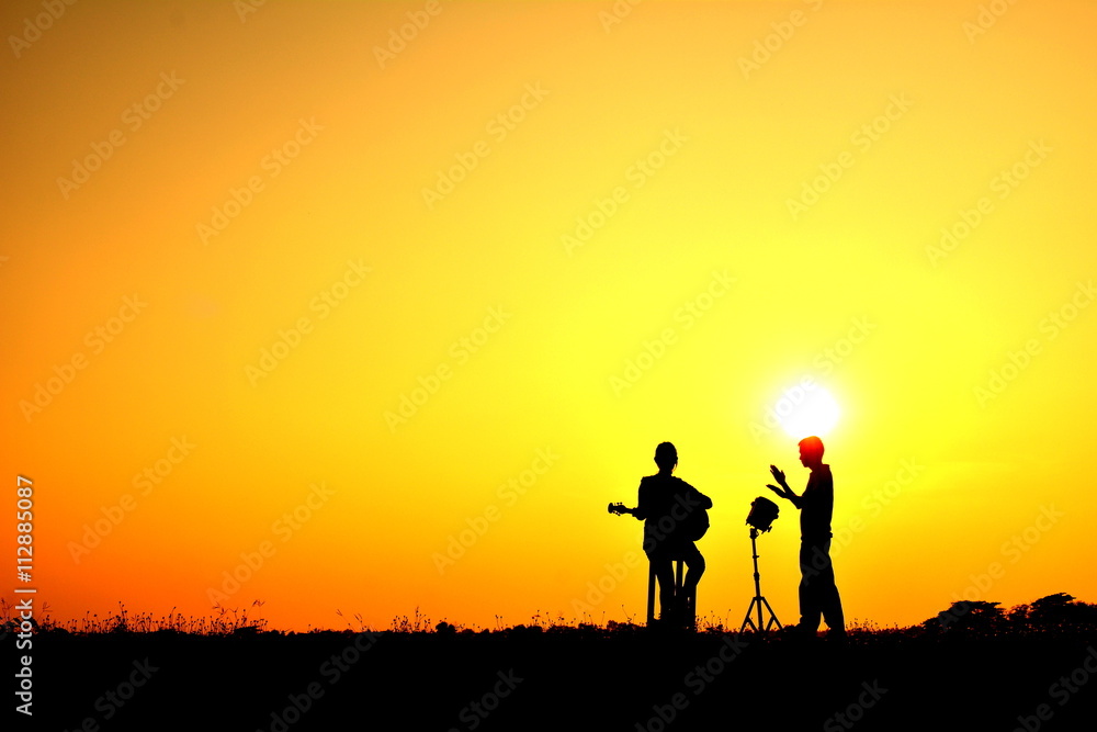 Silhouette people playing musical in the sunset