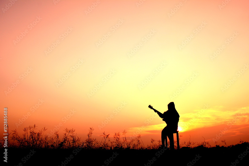 Silhouette women playing guitar in the sunset