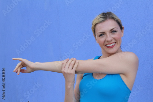 Free style beautiful blond woman stretching on blue background with copy space 