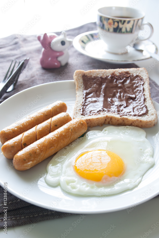 Fototapeta premium Plate of breakfast with egg, sausages, bread and chocolate cream