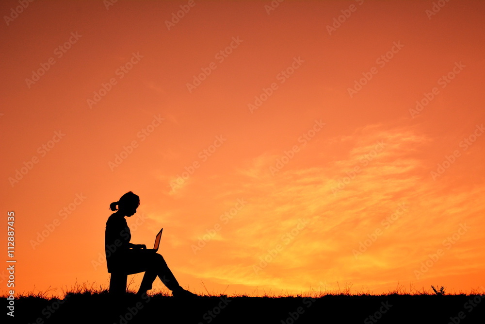Silhouette women using computer at sky sunset Silhouette women using computer at sky sunset