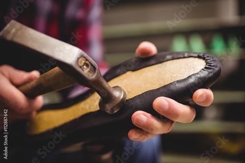 Close up of cobbler making shoes with a hammer photo