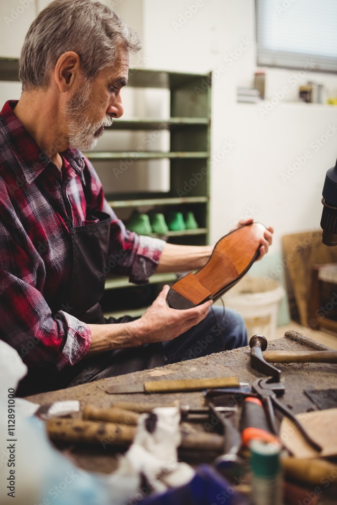 Profile view of cobbler looking the sole of a shoe Stock Photo | Adobe ...