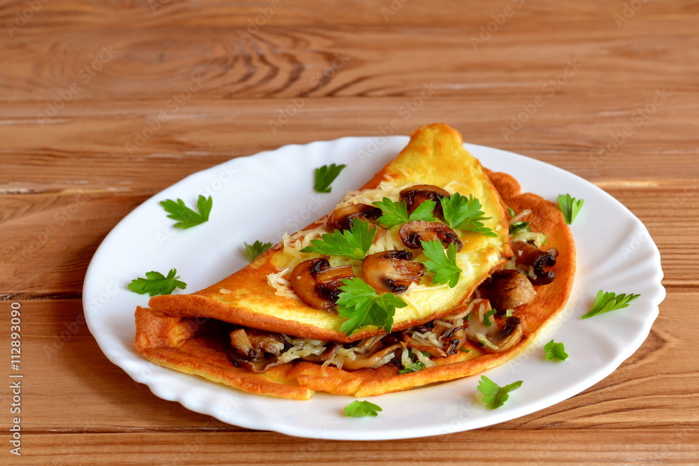 Ruddy scrambled eggs with cheese, fried mushrooms and parsley. Omelet with filling on a plate on wooden background. Fried mushrooms are laid out on an omelet. Leaves of parsley laid on a plate. Ruddy scrambled eggs with cheese, fried mushrooms and parsley. Omelet with filling on a plate on wooden background. Fried mushrooms are laid out on an omelet. Leaves of parsley laid on a plate.