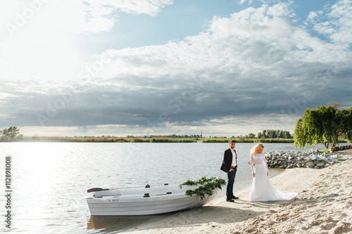 Bride and groom walking near the boat at river