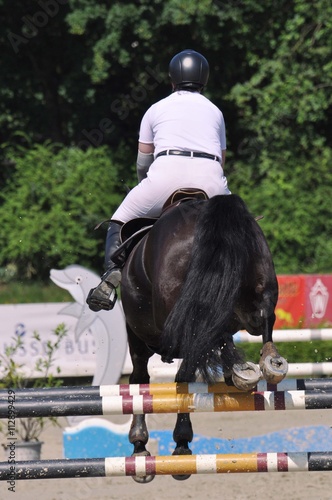 Reiter mit Pferd springen über eine Hürde, auf dem Turnierplatz beim Hürdenspringen  photo