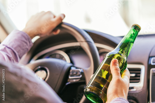 man drinking alcohol while driving the car