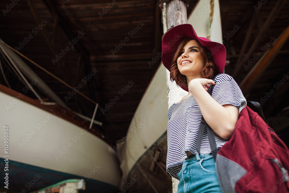Funny Hipster Girl in old boat garage in island, Lots of boats.Trendy Casual Fashion Outfit in summer,spring. Toned Photo.