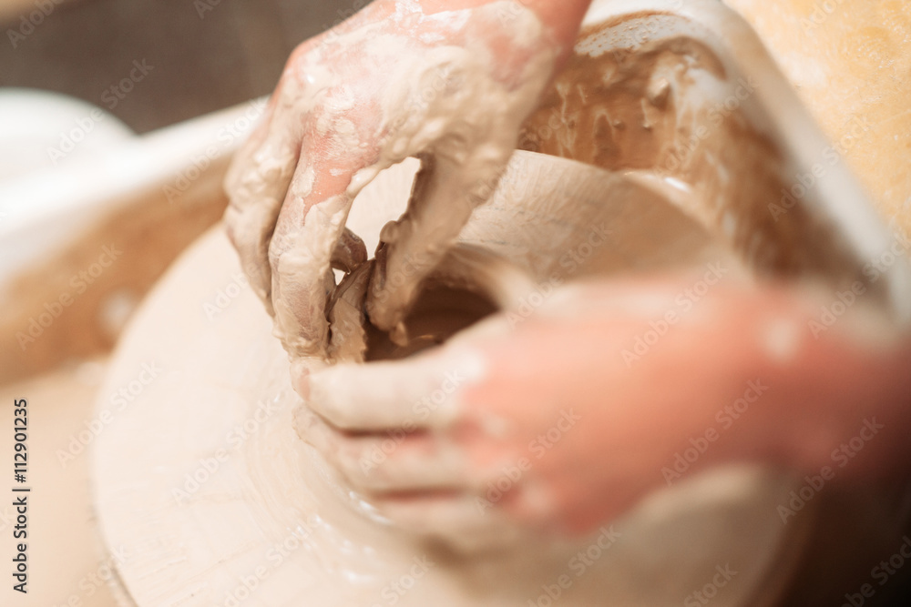 Making ceramics pot dirty hands close-up. Top view on almost ready clay pot and hands, finishing it. Potter finishing clay pot in special trough Making ceramics pot dirty hands close-up. Top view on almost ready clay pot and hands, finishing it. Potter finishing clay pot in special trough