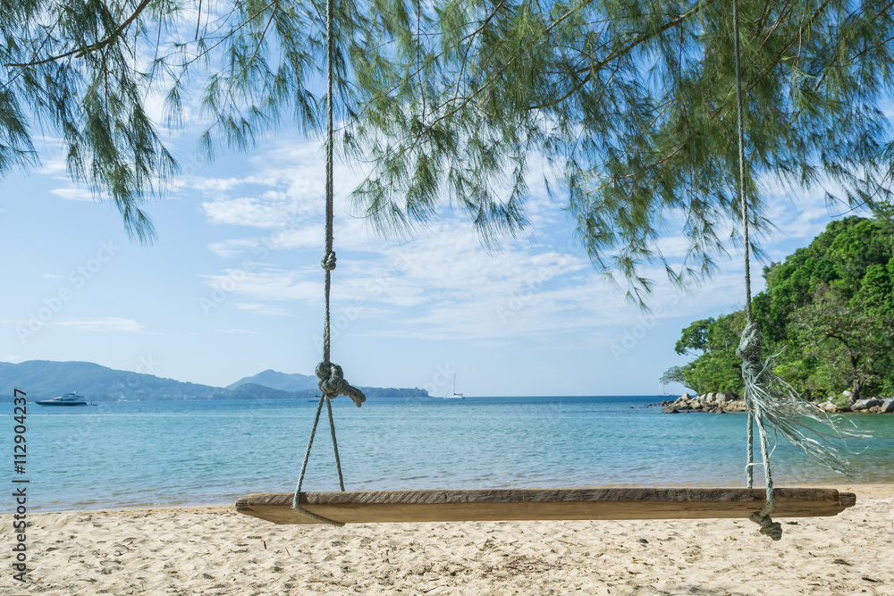 wood swing on the beach with pine tree and blue sky background