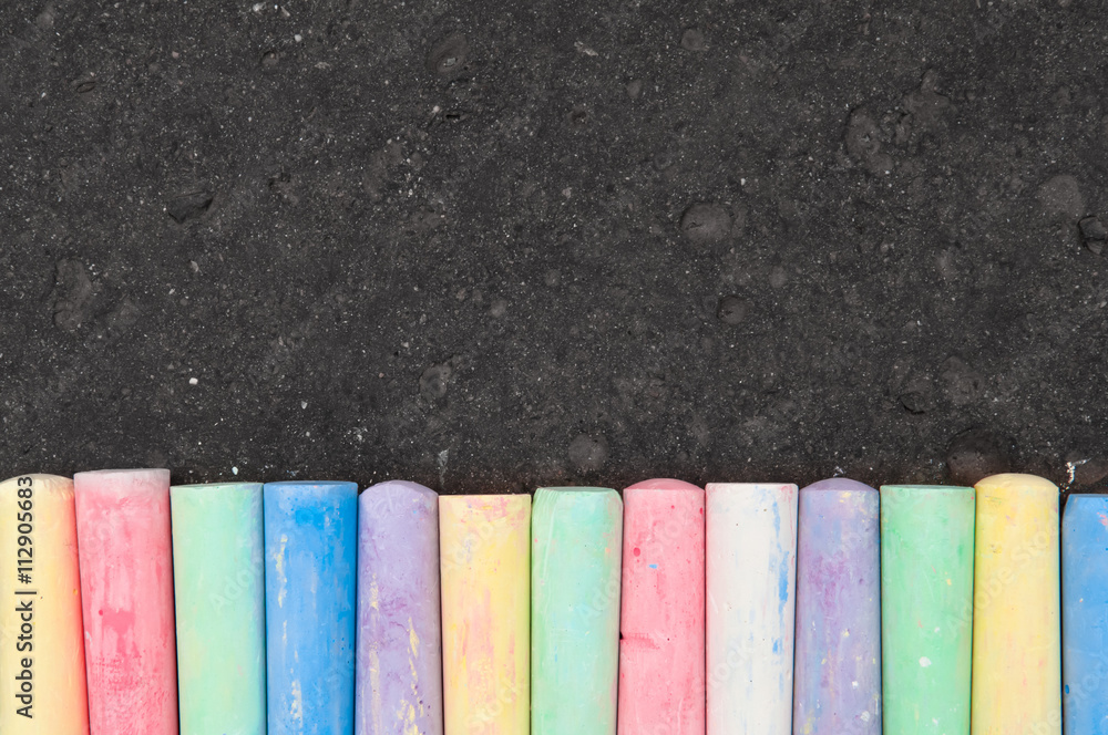 Colorful pastel sidewalk chalk on dark asphalt background. - obrazy, fototapety, plakaty 