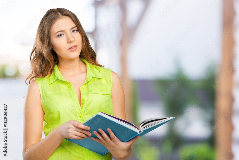 Obraz premium Portrait of a cheerful female teenager with a book