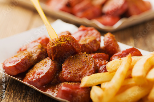 Traditional German currywurst, served with chips on disposable p