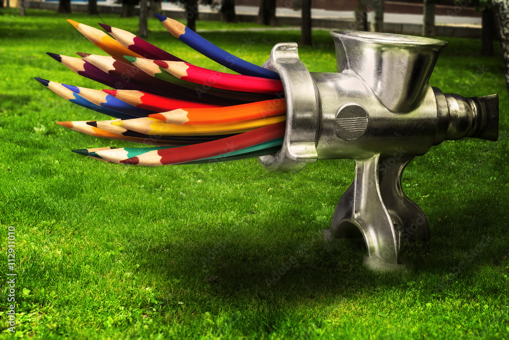 Photo merge  - meat grinder grinds colored pencils on a green lawn. - obrazy, fototapety, plakaty 