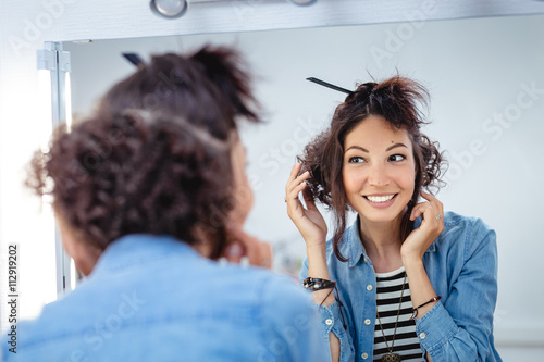 Photography A young woman checks and corrects her hair in the mirror