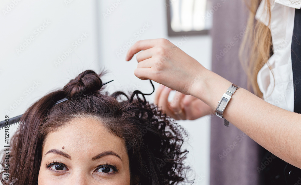 Naklejka premium Close-up of a woman hairdresser making curls at long brown hair