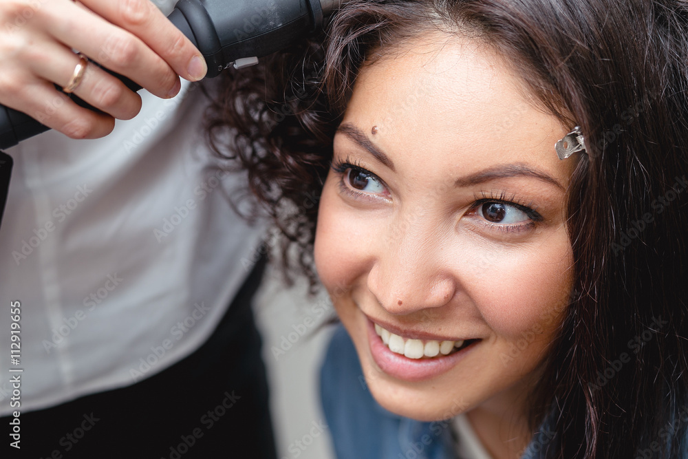A professional hairdresser makes modern fine hairdo with the cur A professional hairdresser makes modern fine hairdo with the cur