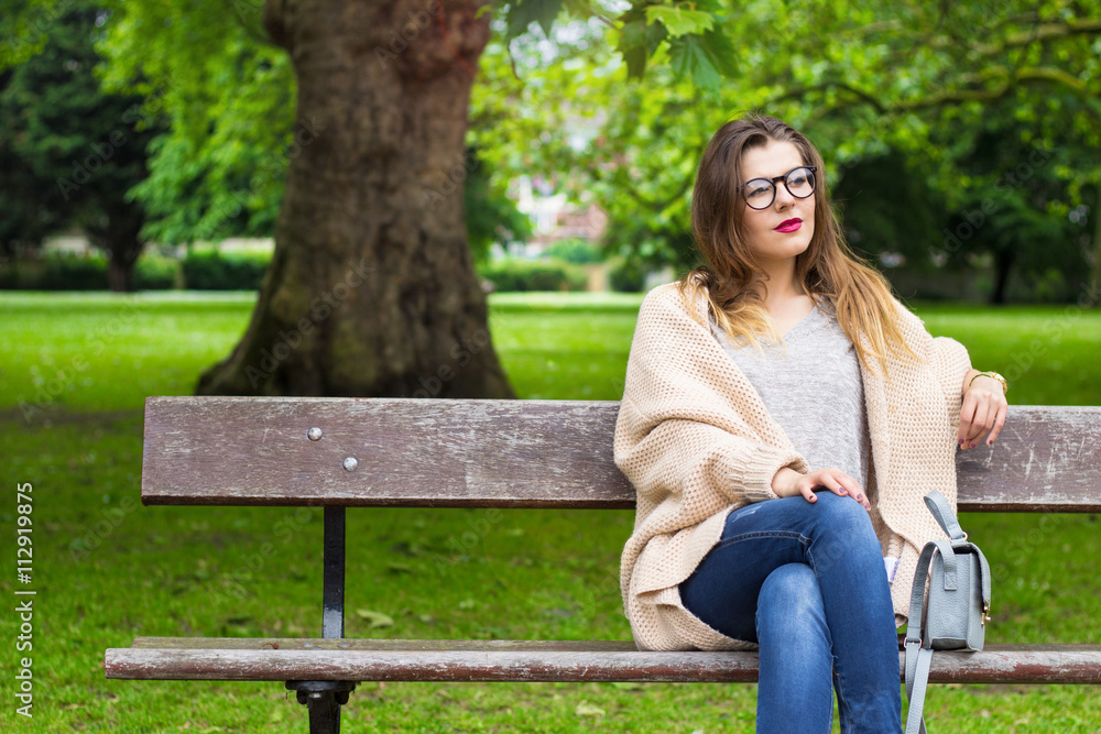 Beautiful smiling girl sitting on the bench in the park Beautiful smiling girl sitting on the bench in the park