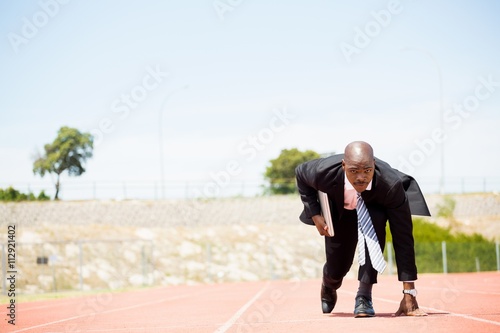 Businessman with laptop ready to run