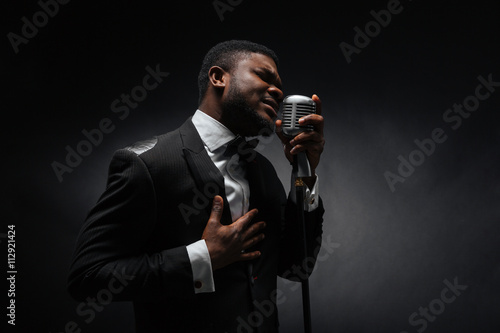 Afro amerian man singing into vintage microphone photo