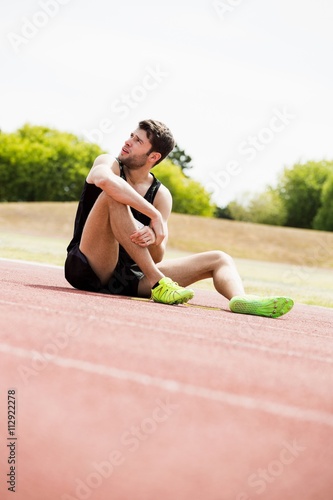 Fototapeta Naklejka Na Ścianę i Meble -  Tired athlete sitting on the running track
