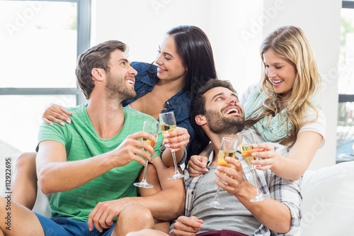 Smiling friends sitting on sofa drinking alcohol © WavebreakmediaMicro