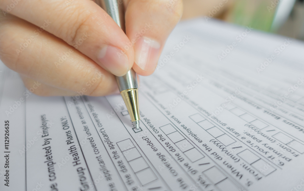 Hand with pen over application form . Hand with pen over application form .