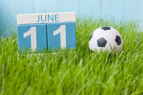 June 11th. Image of june 11 wooden color calendar on green grass background with football outfit. Summer day