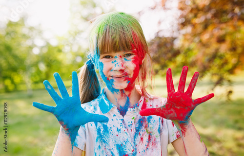 Portrait of a cute girl painted in the colors of Holi festival.