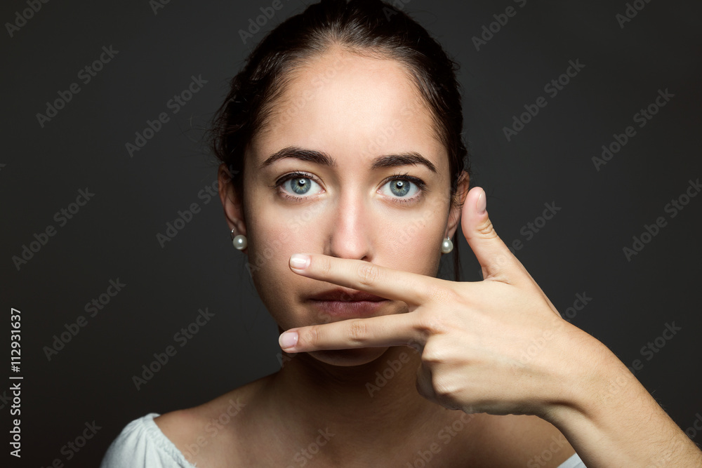 Beautiful young woman covering her mouth with hand. Isolated. Beautiful young woman covering her mouth with hand. Isolated.
