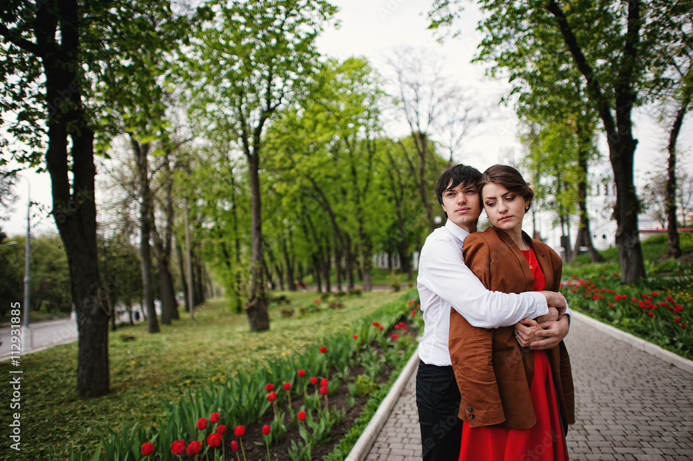 Couple hugging in love at path with tulip flowers garden. Stylis Couple hugging in love at path with tulip flowers garden. Stylis