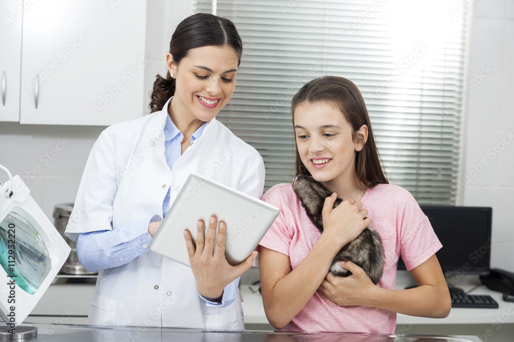 Doctor Showing Tablet Computer To Girl Holding Weasel