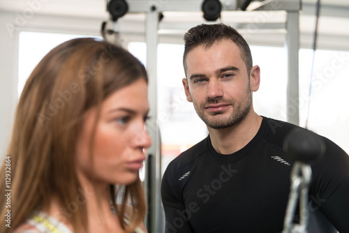 Personal Trainer Helping Client In Gym