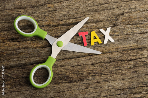 Scissors With TAX Word on Wooden Background